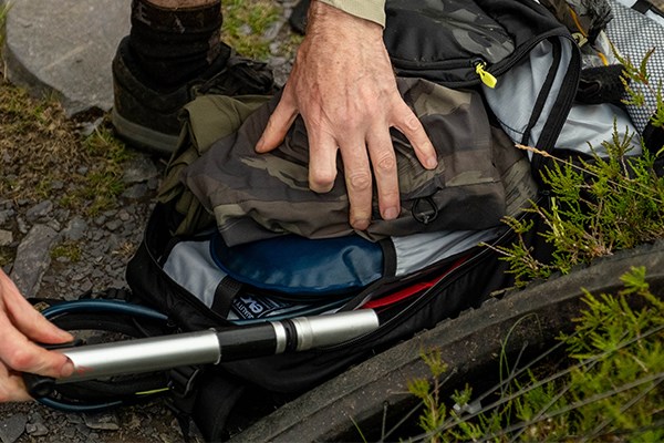 Tyre off the bike pulling a bike pump from a hydration backpack